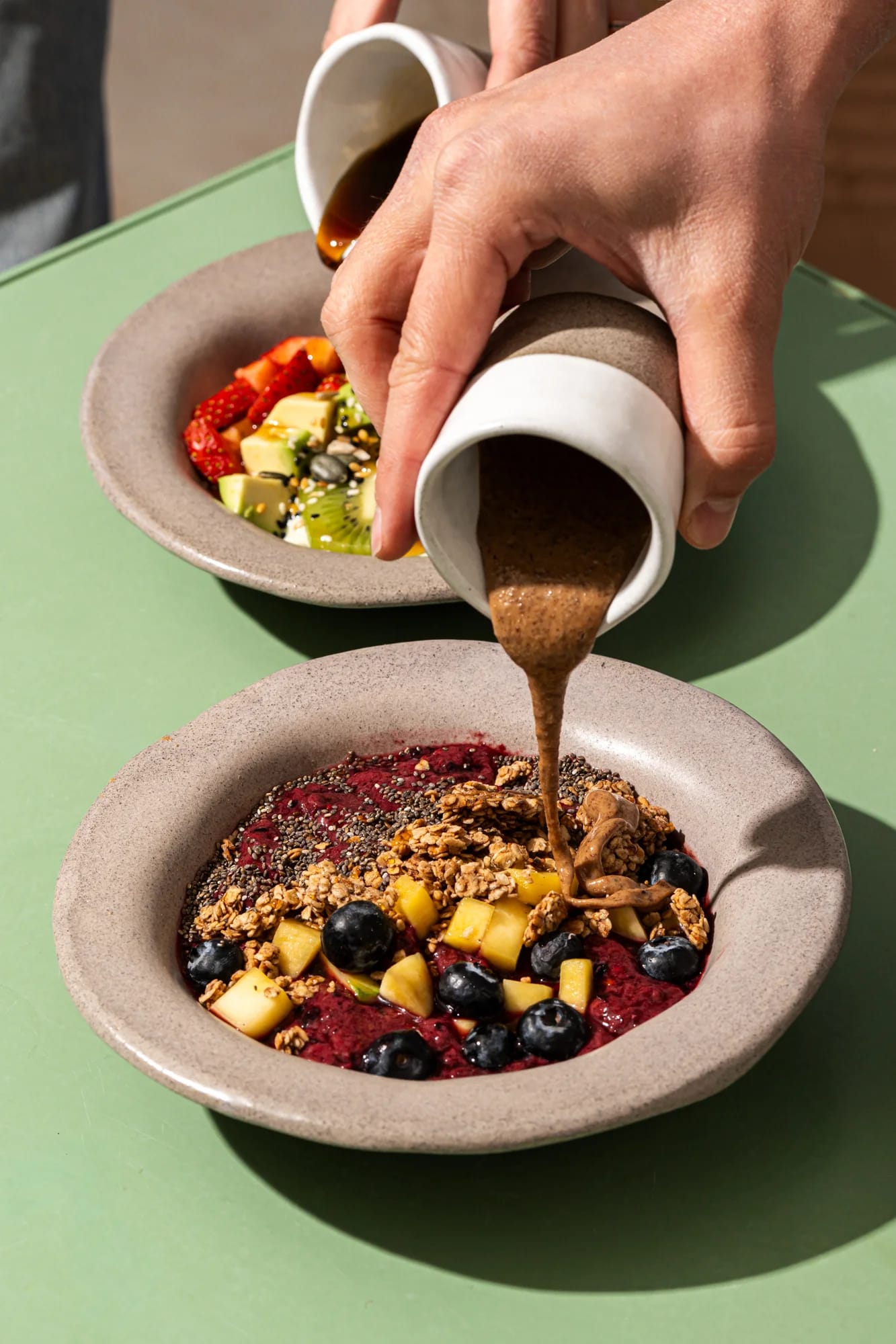 pouring sauce on granola bowl
